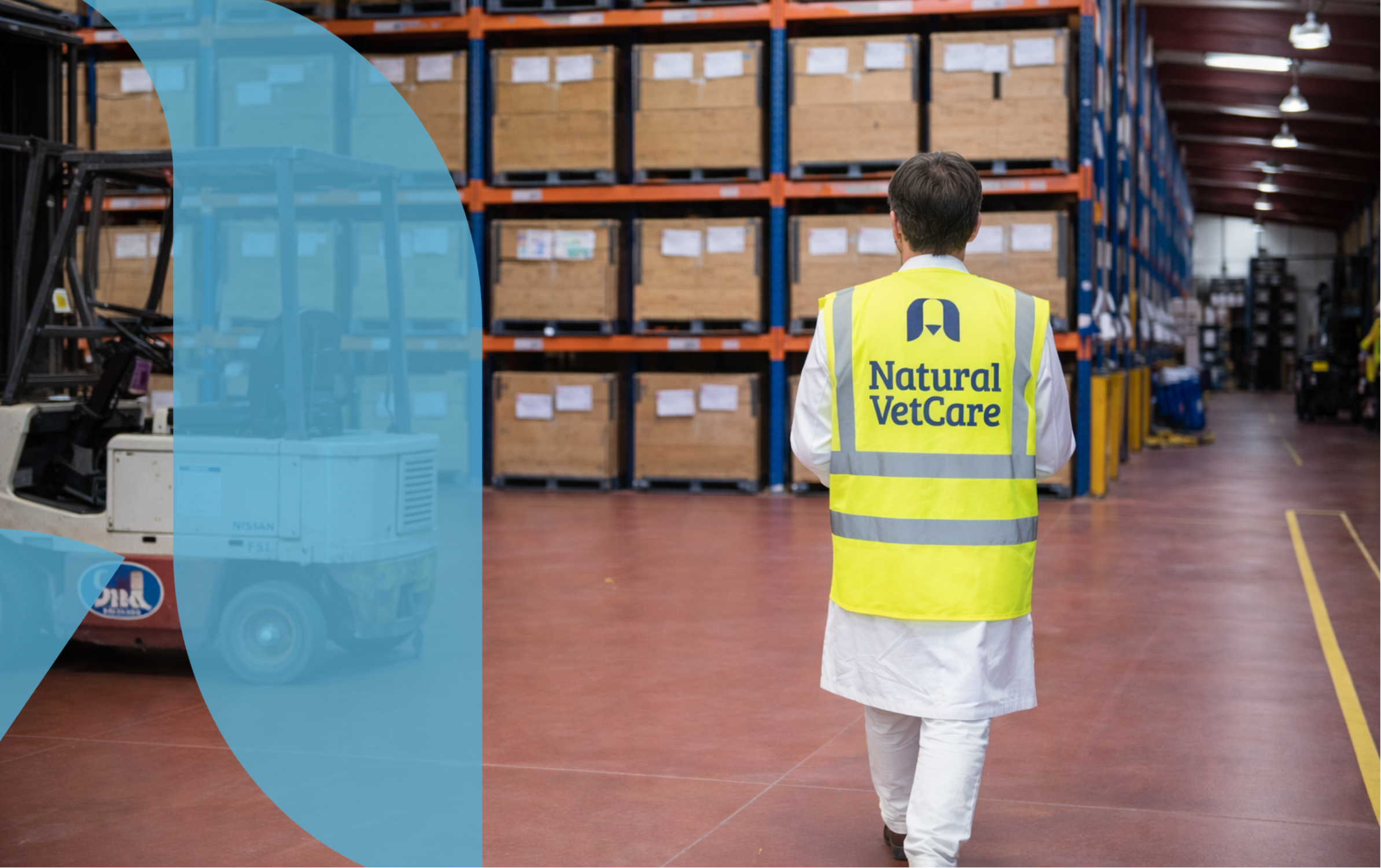 Person wearing a high-visibility vest with 'Natural VetCare' in a warehouse setting.